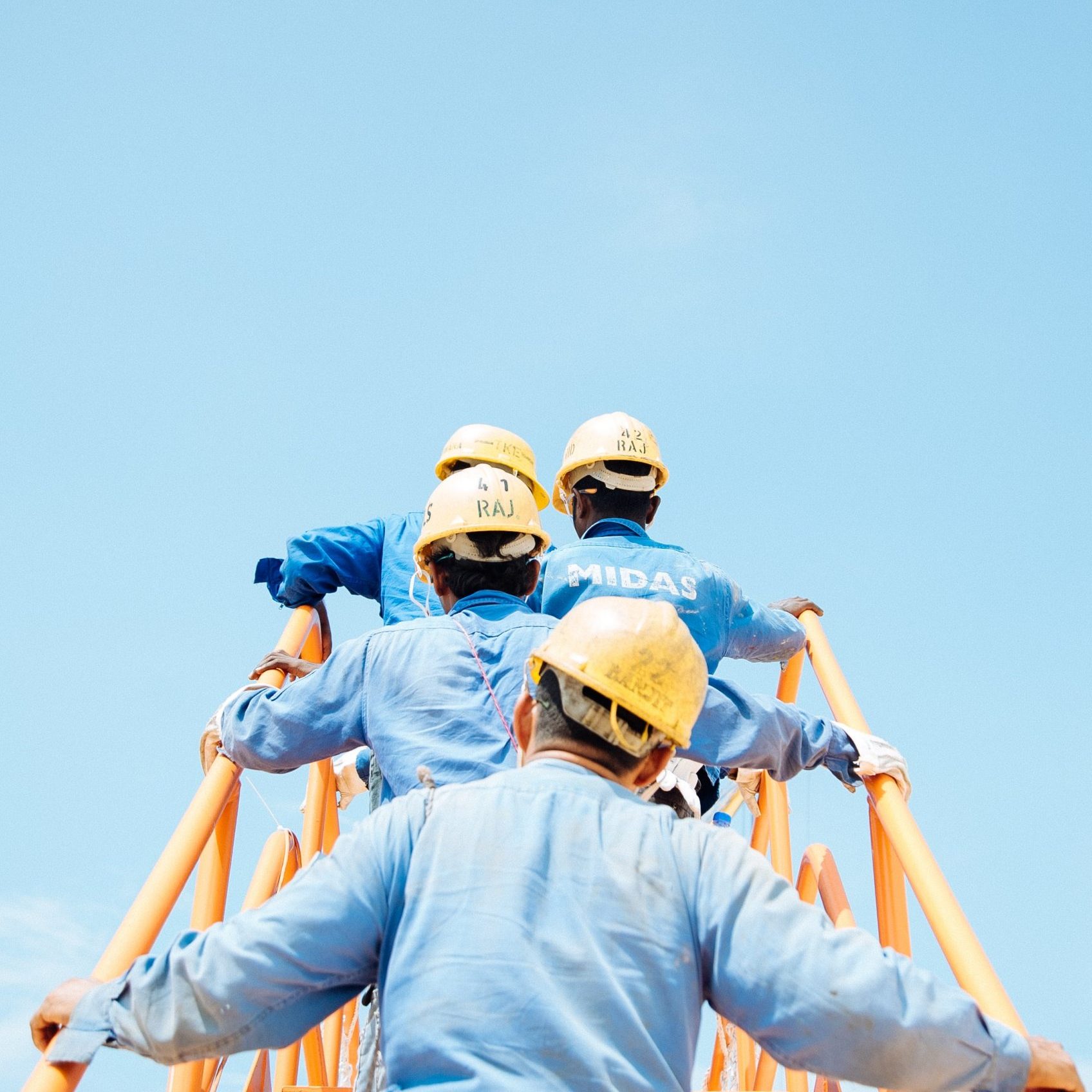 Personnel sur échelle de chantier avec casques jaunes